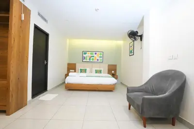 a bedroom with a bed and a chair at IGNIVA Airport Hotel in Calicut