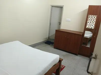 a room with a bed and a mirror and a chair at Formula 1 Premium Villa in Mysore