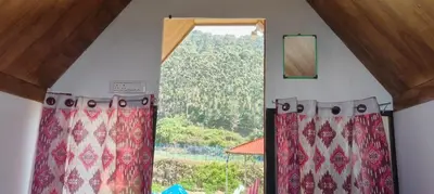 a window with curtains in a room with a view at Moonhills Cabins in Vattavada
