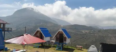 a house with blue windows and a mountain in the background at Moonhills Cabins in Vattavada