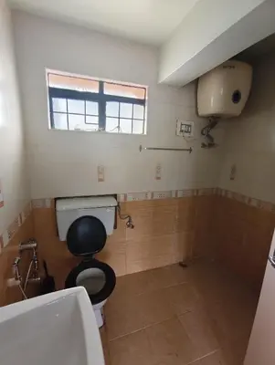 a bathroom with a toilet and a sink and a window at Grays club guest House in Coonoor