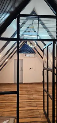 an attic room with a glass door and a wooden floor at Ambience Retreat in Malavalli