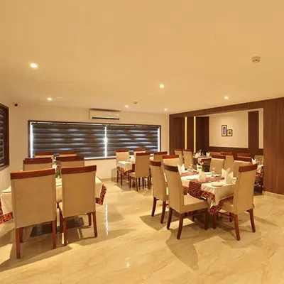a dining room with tables and chairs in a restaurant at Hotel Salkara Chavakkad in Manattala