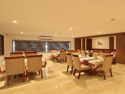 a dining room with tables and chairs in a restaurant at Hotel Salkara Chavakkad in Manattala