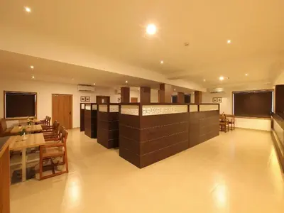 a restaurant with a bar with tables and chairs at Hotel Salkara Chavakkad in Manattala