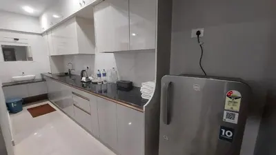 a kitchen with a stainless steel refrigerator and white cabinets at Lavender airport suite in Angamali