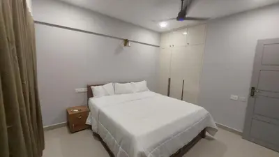a bedroom with a white bed in a room at Lavender airport suite in Angamali
