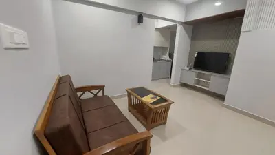 a living room with a couch and a tv at Lavender airport suite in Angamali