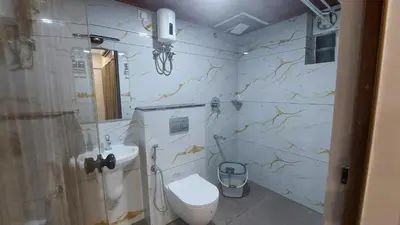 a bathroom with a toilet and a sink at Lavender airport suite in Angamali