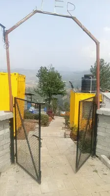 a gate in the side of a building with a view at Janardan Campsite Ooty in Ooty