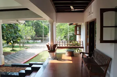 a porch with a bench and a view of a yard at Heritage Home Near Cochin Airport in 5-Acre Farm in Angamali