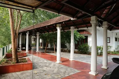 a pavilion with white columns and a building at Heritage Home Near Cochin Airport in 5-Acre Farm in Angamali