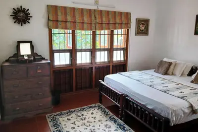 a bedroom with two beds and a dresser and a window at Heritage Home Near Cochin Airport in 5-Acre Farm in Angamali