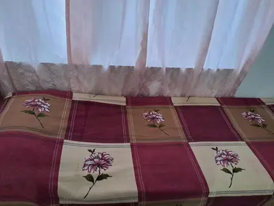 a bed with a quilt with flowers on it at Kunjoose Ladies Hostel in Trichūr