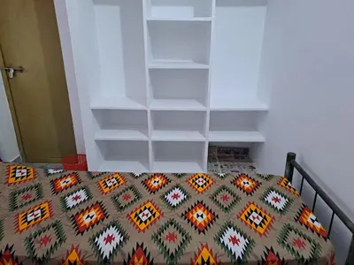 a bedroom with a bed and white shelves at Kunjoose Ladies Hostel in Trichūr