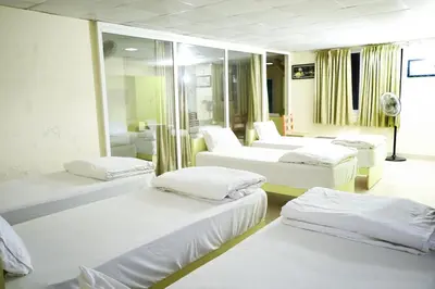 a room with four beds with white sheets at Valparai home villas in Vālpārai