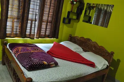 a green bedroom with a bed with pillows on it at Greeneysthomestay in Kushālnagar
