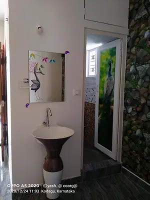 a bathroom with a sink and a picture of a bird at Greeneysthomestay in Kushālnagar
