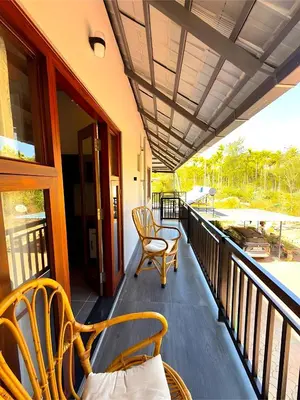 a porch with two chairs and a table at Evara Stays Coorg in Kushālnagar