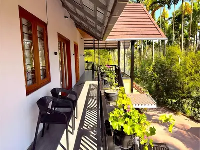 a balcony with a table and chairs and plants at Evara Stays Coorg in Kushālnagar