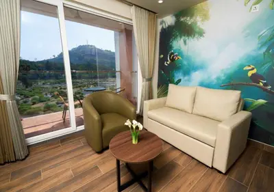 a living room with a couch and a chair and a window at River Bay Athirappilly in Athirappilly
