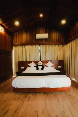 a bedroom with a large bed with a panda bear on it at Wood Panda Luxury Resort Wayanad in Meppādi