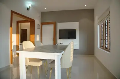 a dining room with a white table and chairs at Gentur Enclave in Mananthavady