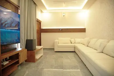 a living room with a white couch and a flat screen tv at Gentur Enclave in Mananthavady