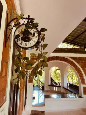 a clock hanging on the side of a building at Mathangi - A Countryside Homestay for Family and Solo Travelers in Kozhikode
