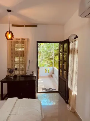 a bedroom with a bed and a door to a patio at Mathangi - A Countryside Homestay for Family and Solo Travelers in Kozhikode
