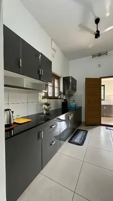 a large kitchen with black cabinets and a large tile floor at Snehanilayam-1 in Trichūr