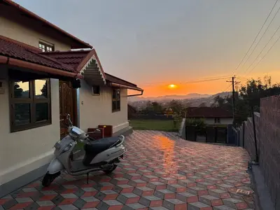a scooter parked outside of a house with the sunset at Blue chill villa in Madikeri