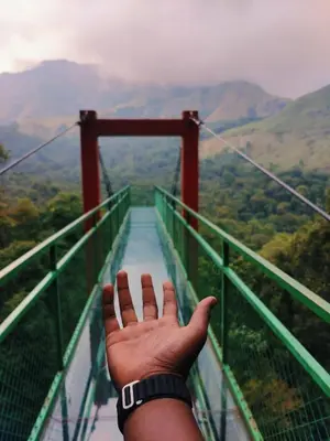 a person holding their hand up on a suspension bridge at Green mountain resort in Meppādi
