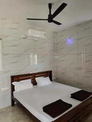 a bedroom with a bed with a ceiling fan at Eshwaraa Cottage in Palani