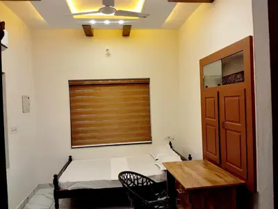a room with a bed and a window and a table at Haritha Bio Park Homestay in Malayāttūr