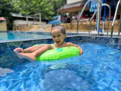 a young boy in a swimming pool with a green raft at Haritha Bio Park Homestay in Malayāttūr