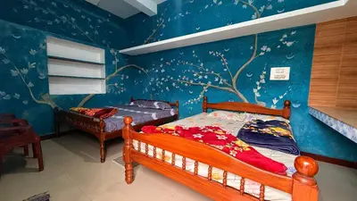 a bedroom with two beds and a blue wall at Adi Home Stay in Vālpārai