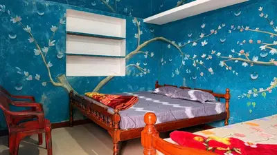 a bedroom with a bed and a blue wall at Adi Home Stay in Vālpārai
