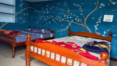 a bedroom with two beds and a tree mural at Adi Home Stay in Vālpārai