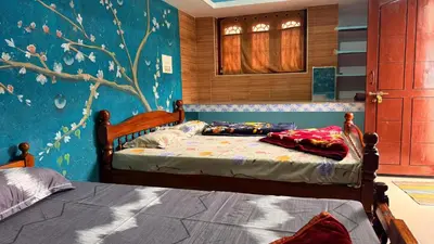 a bedroom with two beds and a blue wall at Adi Home Stay in Vālpārai