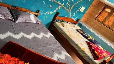 a bedroom with two beds and a blue wall at Adi Home Stay in Vālpārai