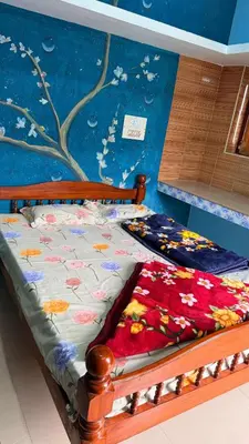 a bed in a room with a tree mural at Adi Home Stay in Vālpārai