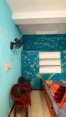 a bedroom with a bed and a chair at Adi Home Stay in Vālpārai