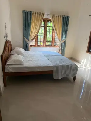 a bedroom with a large bed with a window at Authentic Keralite holiday home for up to 6 in Kāladi