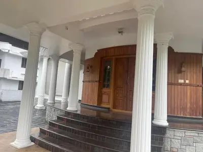 a building with white columns and a wooden door at Authentic Keralite holiday home for up to 6 in Kāladi