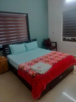 a bedroom with a large bed with a red comforter at Gayathri in Trichūr