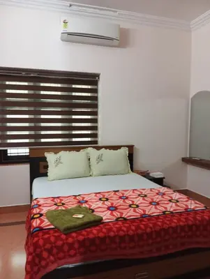 a bedroom with a bed with a red blanket and a window at Gayathri in Trichūr
