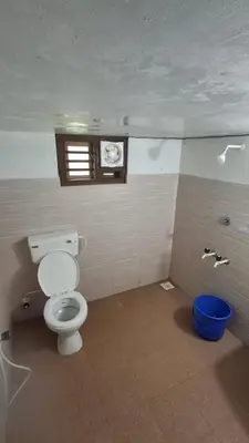 a bathroom with a toilet and a blue bucket at Heritage tharavadu in Mananthavady