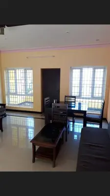 a room with a table and chairs and windows at The Misty Woods in Kotagiri