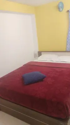a bedroom with a bed with a red comforter at White House Cottage in Ooty